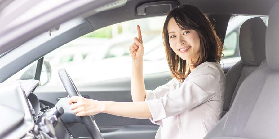 笑顔で車を運転する女性の写真