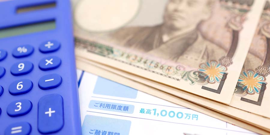 「ご利用限度額1000万円」と書かれた資料とお金、電卓の画像