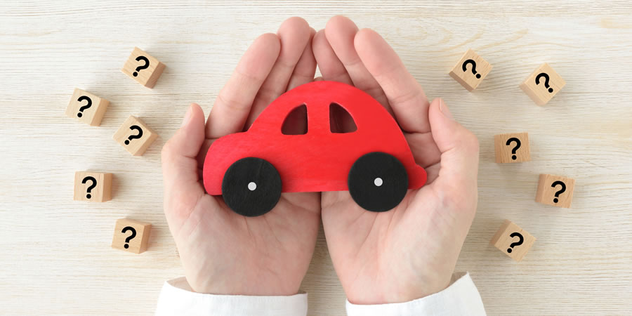 虫眼鏡で車を見る男性